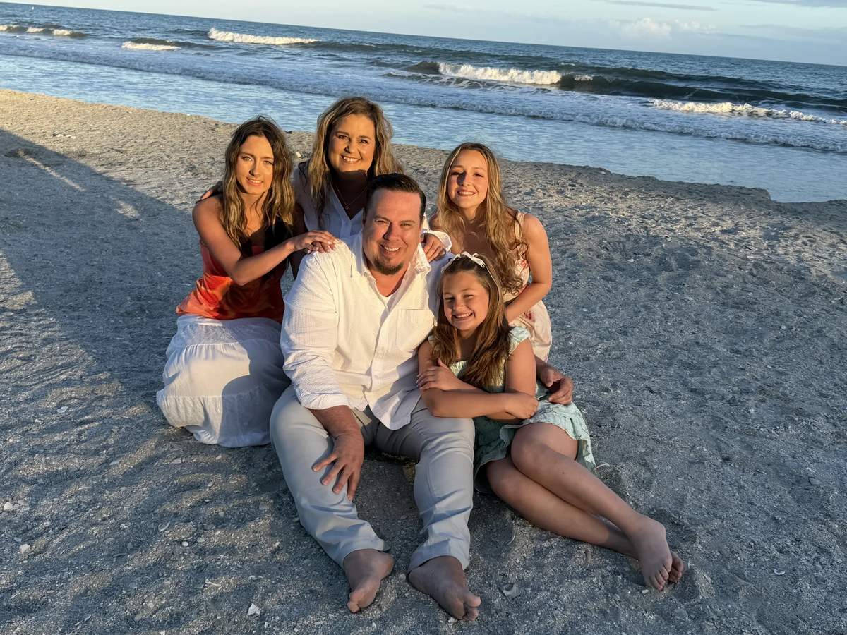 Cliff Johnson and his family sitting together on a beach