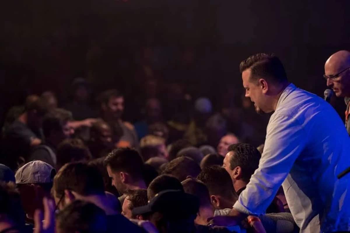 Cliff Johnson prays with people gathered near the front of a church